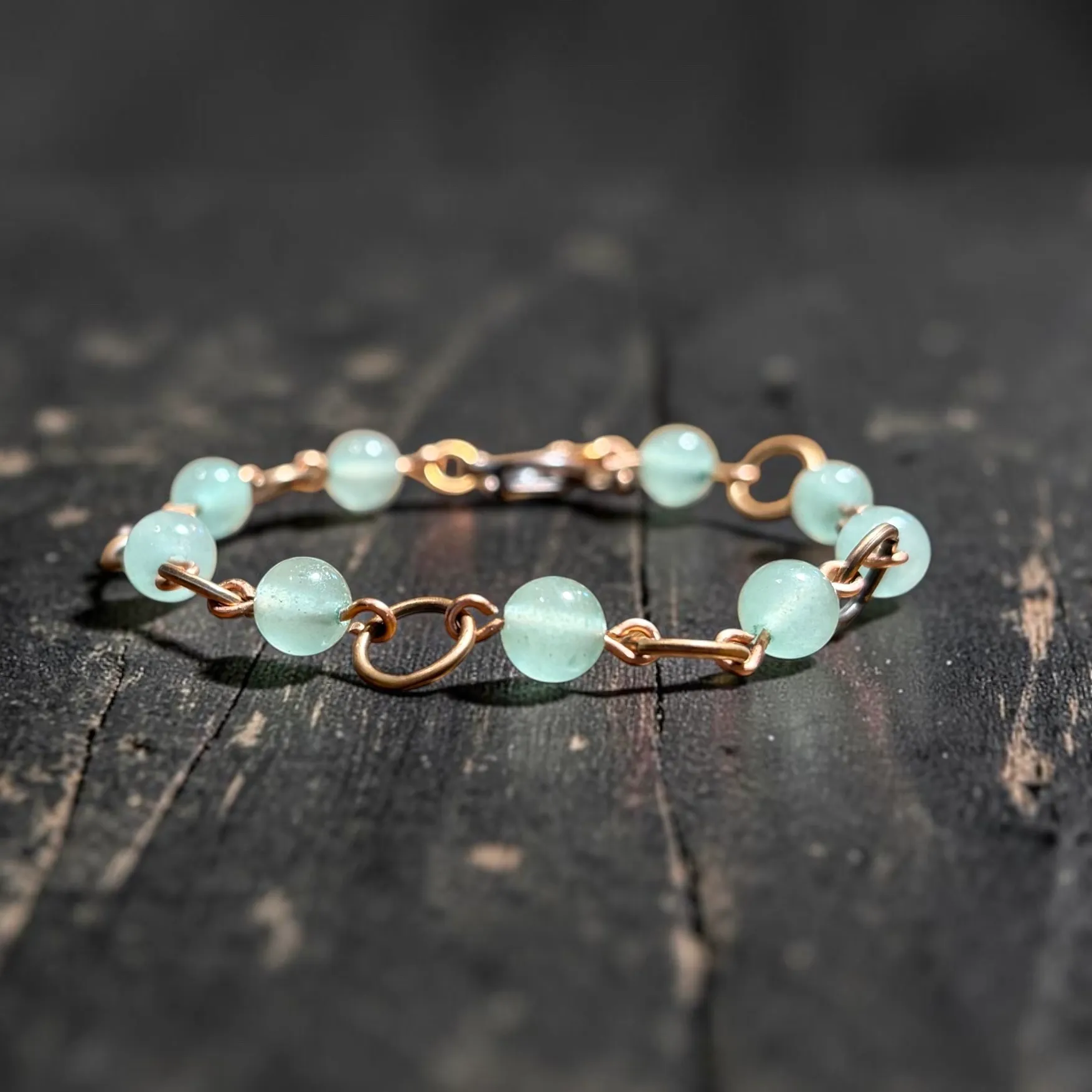 Copper bracelet with pale green translucent aventurine beads and copper link connectors.